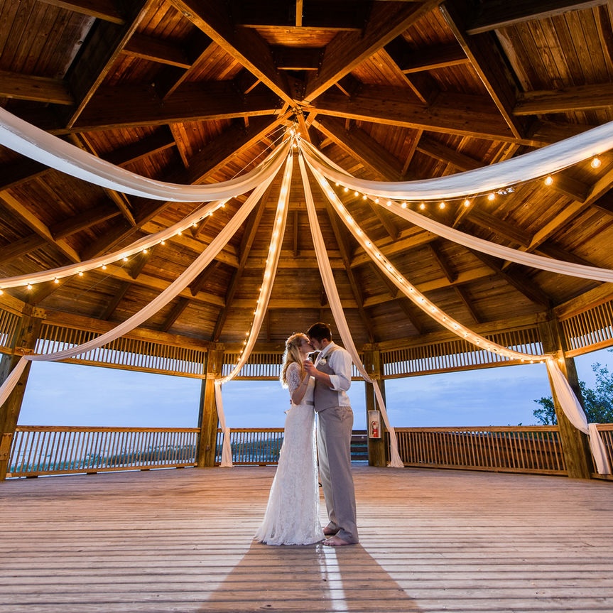 A couple dancing in a large gazebo under draped string lights