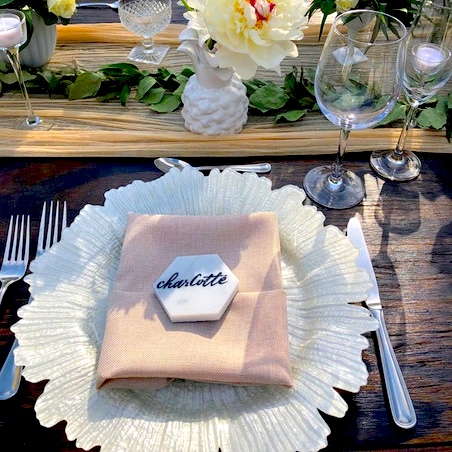 A pink napkin atop a white charger plate with rippled edges